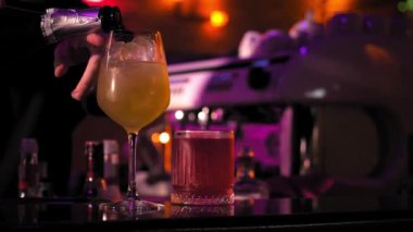 Barmenin yakın çekimi dikkatle şampanyayı bardaki buzlu hazır kokteyl bardağına dolduruyor. Kokteyl yapma kavramı