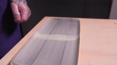 Şef sushi, mikroyeşil ve wasabi ile sushi servis etmek için dikdörtgen tabak dekore ediyor. Yiyecek kavramı
