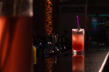 Buzlu, samanlı, biberiyeli ve bardakta köpüklü çilekli alkollü kokteyl loş bir ışıkta bardakta..