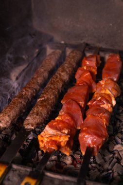 İştah açıcı kebap ya da taze etten yapılmış şiş kebap yakın plan ve lula kebabı mangalda dumanla pişiriliyor. Dikey fotoğraf