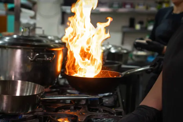 Die Hände Des Kochs Halten Einen Wok Mit Feuer Über lizenzfreie Stockbilder