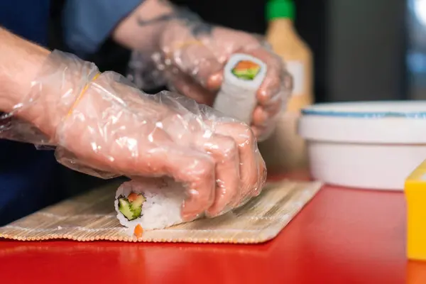 Chef Bereidt Sushi Met Rode Vis Komkommers Nori Een Rood Stockfoto