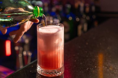 Barmene yakın plan çilekli kokteyl, buz ve köpüklü bardağa karbonatlı su dökerken. Barmen kokteyl hazırlıyor.