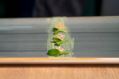 Şef sushi, mikroyeşillik ve wasabi ile suşi servis etmek için dikdörtgen bir tabak dekore ediyor. Yiyecek kavramı
