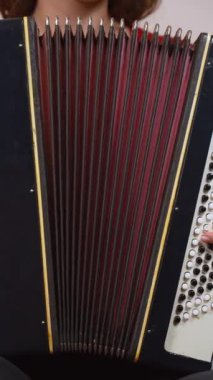 Geleneksel akordeon çalmada usta müzisyenlerin ellerini gösteren yakın plan çekimde, parmaklarının ve enstrümanın karmaşık hareketlerinin vurgulanması. Dikey video
