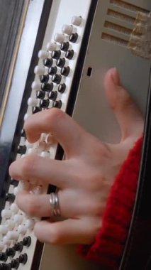 Geleneksel akordeon çalmada usta müzisyenlerin ellerini gösteren yakın plan çekimde, parmaklarının ve enstrümanın karmaşık hareketlerinin vurgulanması. Dikey video