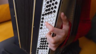 Geleneksel akordeon çalmada usta müzisyenlerin ellerini gösteren yakın çekim, parmaklarının ve enstrümanın karmaşık hareketlerini vurgulayan.