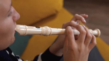 Genç müzisyen flüt çalıyor, farklı notalar için uygun parmak pozisyonlarını gösteriyor, enstrümanı detaylı bir şekilde görüyor ve çalma tekniğini gösteriyor.