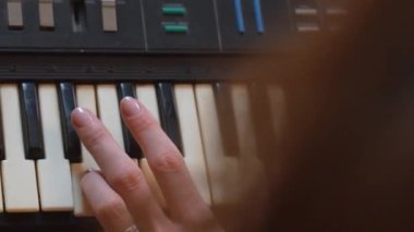 Kadın müzisyen, karmaşık parmak yerleştirmeleri ve antik elektronik sentezleyici enstrümanlarının tuşlarında hassas el hareketleri kaydederek klavye çalma pratiği yapıyor. dikey video