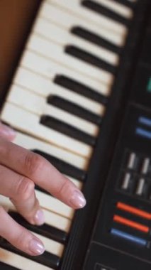 Kadın müzisyen, karmaşık parmak yerleştirmeleri ve antik elektronik sentezleyici enstrümanlarının tuşlarında hassas el hareketleri kaydederek klavye çalma pratiği yapıyor. dikey video