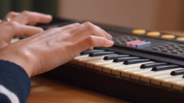 Kadın müzisyen, karmaşık parmak yerleştirmeleri ve antik elektronik sentezleyici enstrümanlarının tuşlarında hassas el hareketleri kaydederek klavye çalma pratiği yapıyor..
