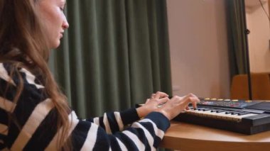 Elektronik klavye sentezleyicisi çalan bayan müzisyen sıcak, rahat oturma odasında nostaljik bir müzik atmosferi yaratarak melodik kompozisyon yoluyla yaratıcı tutkularını ifade ediyor..