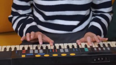 Elektronik klavye sentezleyicisi çalan bayan müzisyen sıcak, rahat oturma odasında nostaljik bir müzik atmosferi yaratarak melodik kompozisyon yoluyla yaratıcı tutkularını ifade ediyor..