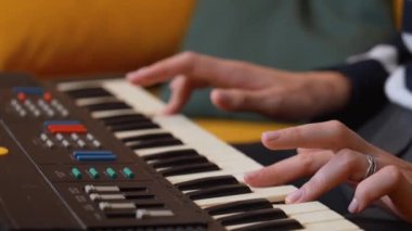 Profesyonel bayan müzisyen elektronik klavye çalıyor, rahat çizgili süveter giyerken rahat ev stüdyo ortamında tutkulu melodik kompozisyonlar yaratıyor.