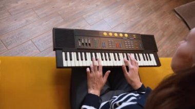 Elektronik klavye sentezleyicisi çalan bayan müzisyen sıcak, rahat oturma odasında nostaljik bir müzik atmosferi yaratarak melodik kompozisyon yoluyla yaratıcı tutkularını ifade ediyor..