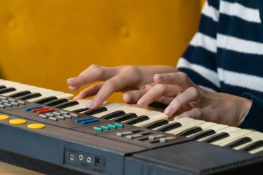 Klasik bir klavye sentezleyicisini ustalıkla çalan ellerin yakın plan görüntüsü, bir stüdyo ortamında ilgi çekici bir müzikal performans sırasında karmaşık elektronik sesler ve melodiler yaratıyor.