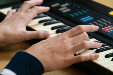 Elektronik klavyeyi ustalıkla çalan kadınların yakın plan görüntüsü müzik yaratma sanatını ve müzikal ifadeyi yönlendiren tutkuyu vurguluyor.