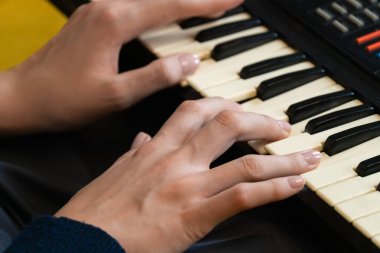 Kadın müzisyenin ellerinin klasik bir sentezleyici klavyesini ustaca çalarken yakın plan görüntüsü profesyonel bir kayıt stüdyosu ortamında büyüleyici bir elektronik müzik üretiyor.