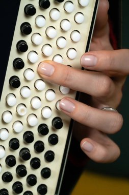 Bir müzisyenin akordeon çalan elinin ayrıntılı görüntüsü, düğmelerin karmaşık düzenine odaklanıyor. Sahne, bu enstrümanı çalmaktaki hassasiyet ve beceriyi yakalar. Dikey fotoğraf