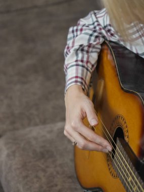 Bir müzisyenin ellerini, akustik gitarın tellerine ustalıkla yerleştirerek güzel bir akor ya da büyüleyici bir melodi çalmaya hazırlarken yakın plan görüntüsü. Dikey fotoğraf