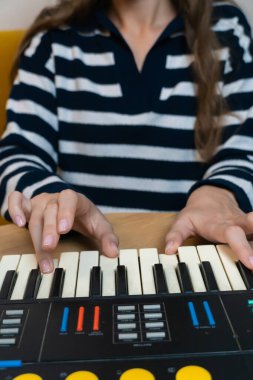 Elektronik müziğin özünü yakalamak, müzisyenin elleri ustalıkla klasik bir sentezleyici klavye çalıyor, yaratıcı bir stüdyo ortamında nostaljik bir retro hissi uyandırıyor. Dikey fotoğraf