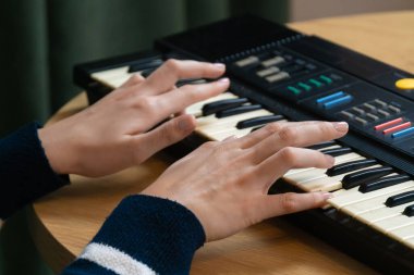 Klasik bir elektronik sentezleyici klavyesini ahşap bir masanın üstünde çalarken müzik besteleyen kadın müzisyen yaratıcılığı ve tutkuyu genel bir perspektiften yakalıyor..