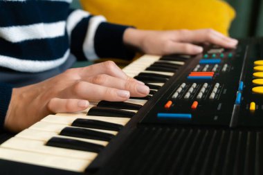 Kadın ellerinin usta bir şekilde klasik bir sentezleyici çalarken, rahat bir ev stüdyosunda veya profesyonel kayıt ortamında canlı elektronik müzik yaparken yakın plan görüntüsü.