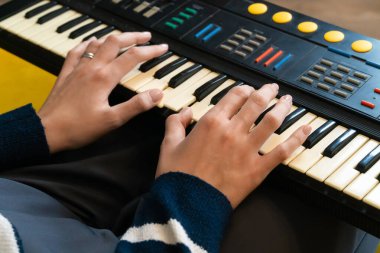 Kadın ellerinin ustalıkla bir sentezleyiciyi çalması, müzik yeteneğini ve tutkusunu ifade etmesi ve ev stüdyosunda büyüleyici melodiler yaratması.