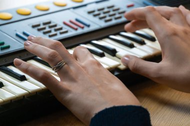 Klasik bir sentezleyici klavye çalan, ev stüdyosunda elektronik müzik yaratan, müzikal yaratıcılık ve tutku içeren kadın ellerinin yakın çekimi.