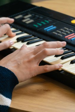 Elektronik klavyeyi ustalıkla çalan kadın ellerinin yakın plan görüntüsü müzik yaratma sanatını ve müzikal ifadeyi yönlendiren tutkuyu vurguluyor. Dikey fotoğraf
