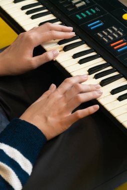 Kadın müzisyenin ellerinin klasik bir sentezleyici klavyesini ustaca çalarken yakın plan görüntüsü profesyonel bir kayıt stüdyosu ortamında büyüleyici bir elektronik müzik üretiyor.