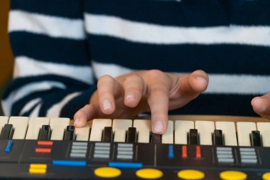 Klasik bir klavye sentezleyicisini ustalıkla çalan ellerin yakın plan görüntüsü, bir stüdyo ortamında ilgi çekici bir müzikal performans sırasında karmaşık elektronik sesler ve melodiler yaratıyor.