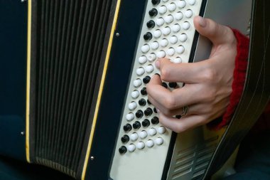 Geleneksel akordeon çalan bir müzisyenin elinin yakın çekimi enstrümanın karmaşık detaylarını ve müzik yaratma becerisini gözler önüne seriyor.