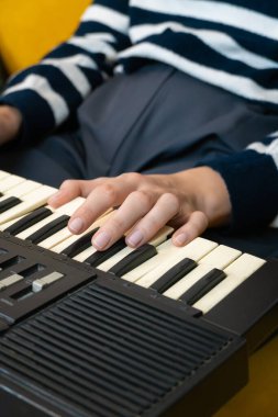 Klasik bir sentezleyicinin tuşları üzerinde dans eden parmaklar, karmaşık melodiler ve zengin elektronik sesler yaratıyor, kendini adamış bir müzisyenin beceri ve tutkusunu sergiliyor. Dikey fotoğraf
