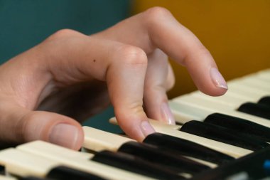 Kadın ellerinin bir sentezleyici klavyesini ustalıkla çalarken, melodileri hazırlarken ve yaratıcı sürecin tadını çıkarırken yakından görüntüsü ilham dolu bir ev ortamında