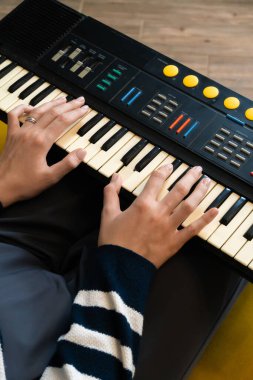 Kadın ellerinin ustalıkla bir sentezleyiciyi çalması, müzik yeteneğini ve tutkusunu ifade etmesi ve ev stüdyosunda büyüleyici melodiler yaratması.