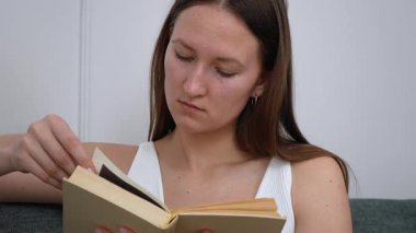 Rahat koltukta otururken kitap okuyan rahat bir kadın, pozisyonlarını değiştiriyor ve boş zamanlarında yüz ifadeleri sergiliyor.