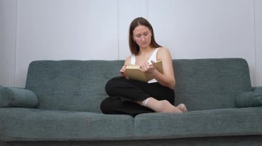 Genç bir kadın kendini kitap okumaya, koltukta rahatça oturmaya, sakin bir yaşam tarzına ve sakin bir kişisel rahatlama anına kaptırır.