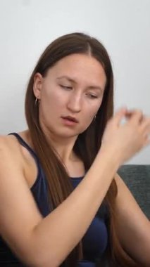 Genç bir kadın evde dinleniyor, doğal tırnaklarını dikkatlice törpülüyor ve şekillendiriyor rahat gri koltukta oturuyor, kişisel güzelliğini ve sağlığını gözler önüne seriyor.