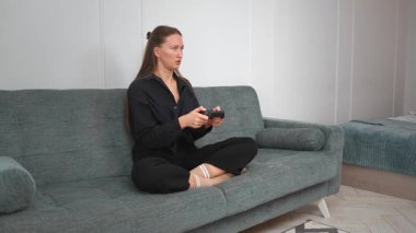 Genç kadın video oyununa çok bağlıydı. Oturma odasındaki koltukta rahatça oturuyordu. Elinde kablosuz oyun kumandası vardı.