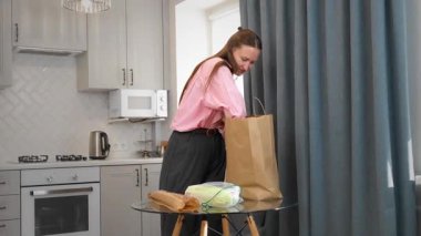 Marketten alışveriş yaptıktan sonra marketten alışveriş yapan bir kadın. Online alışveriş yapan genç memnun olmuş kurye teslimatıyla internetten sipariş edilen ürünlerin paketini açıyor.