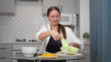 Kadın salata hazırlıyor, sebze doğruyor, mutfakta ahşap bir tahtanın üzerinde Çin lahanası kesiyor, aşçılık becerilerini ön plana çıkarıyor. dikey video
