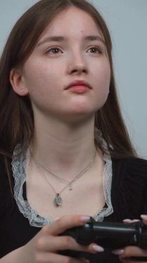 Genç kız oturma odasındaki rahat koltukta bacak bacak üstüne atarak bilgisayar oyunu oynamaktan hoşlanıyor. Ekranda olanlara odaklanıyor.