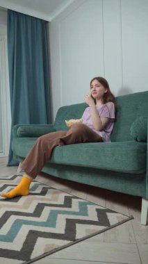 Kanepesinde rahat bir şekilde, genç bir kadın nişanlı bir film izlerken bir kase patlamış mısırın keyfini çıkarıyor. İfadeleri anlatılan hikayenin dikey videosuyla değişiyor.