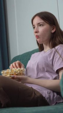 Rahat genç bir kadın oturma odasındaki kanepede rahatça uzanıyor, hafta sonları dinlenirken en sevdiği filmin tadını çıkarırken patlamış mısır yiyor.