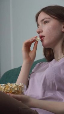 Rahat genç bir kadın oturma odasındaki kanepede rahatça uzanıyor, hafta sonları dinlenirken en sevdiği filmin tadını çıkarırken patlamış mısır yiyor.