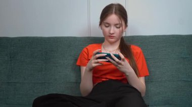 Genç kız rahat ev koltuğunda dinleniyor, akıllı telefon elinde, sosyal medyada geziniyor ya da umursamaz davranışlarla mobil oyun oynuyor.