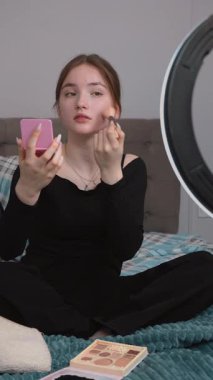 Güzellik etkisinde olan genç kız makyaj dersini kaydediyor, makyaj yapıyor ve çevrimiçi izleyiciler için halka ışığı ve akıllı telefonla dijital içerik yaratıyor. Nehir. dikey video