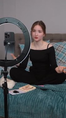 Genç vlogger çocuk kanalı için video blogu yapıyor. Güzellik blogları, teknoloji ve insanlar konsepti - mutlu gülümseyen kız blogcu, zil ışığı ve akıllı telefon ile evde dikey video uygulaması