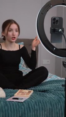 Genç vlogger çocuk kanalı için video blogu yapıyor. Güzellik blogları, teknoloji ve insanlar konsepti - mutlu gülümseyen kız blogcu, zil ışığı ve akıllı telefon ile evde dikey video uygulaması
